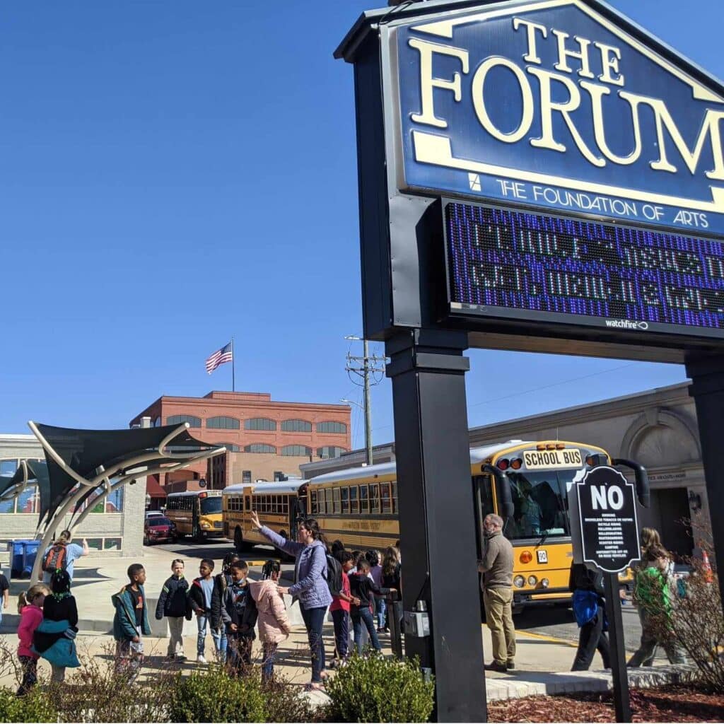 A group of students getting off of a school bus to visit The Forum Theater