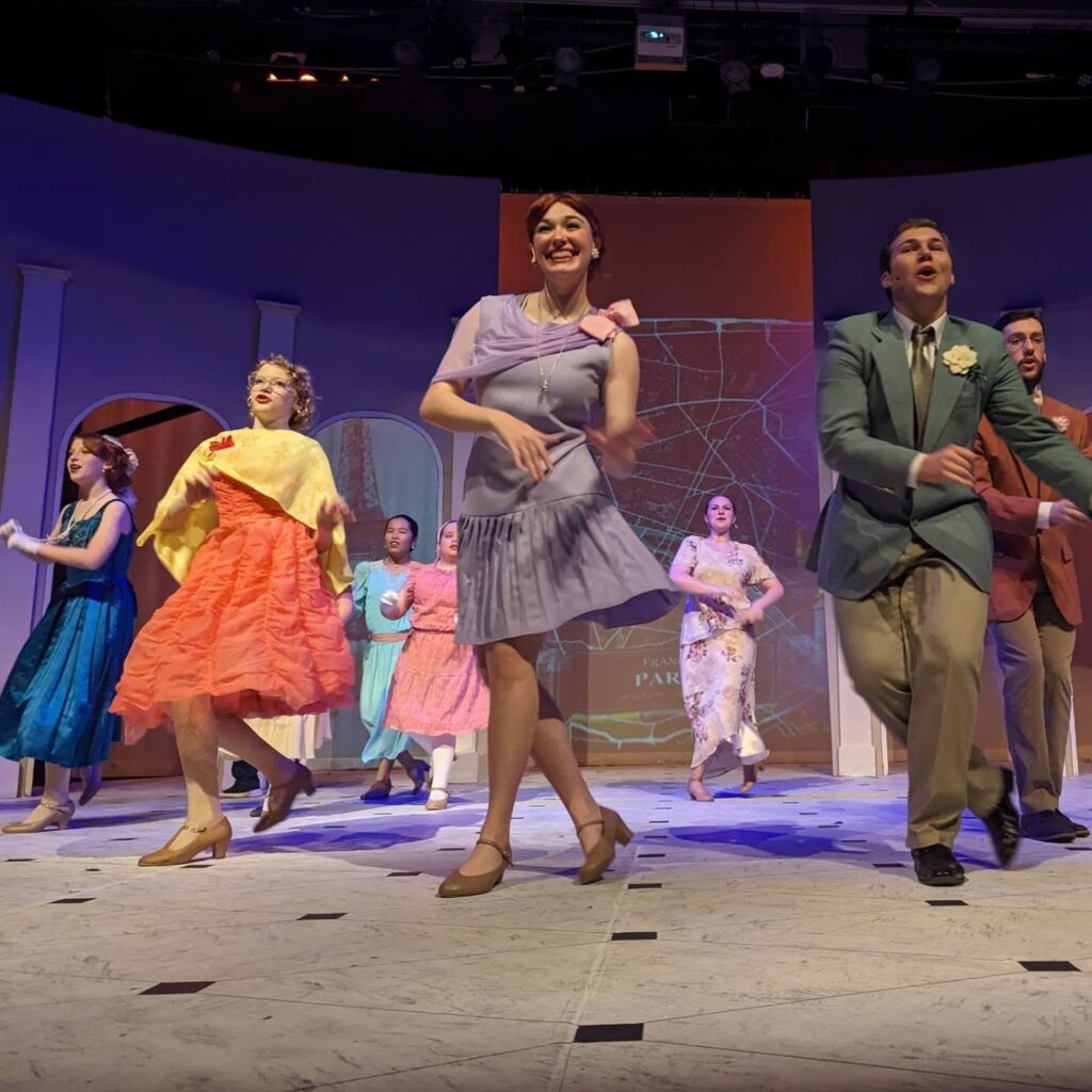 Group of people in character dancing and singing during a musical